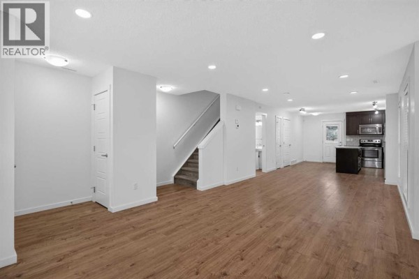 Open concept main floor with living area, stairs, and kitchen access. - 53 Cranford Way Se, Calgary
