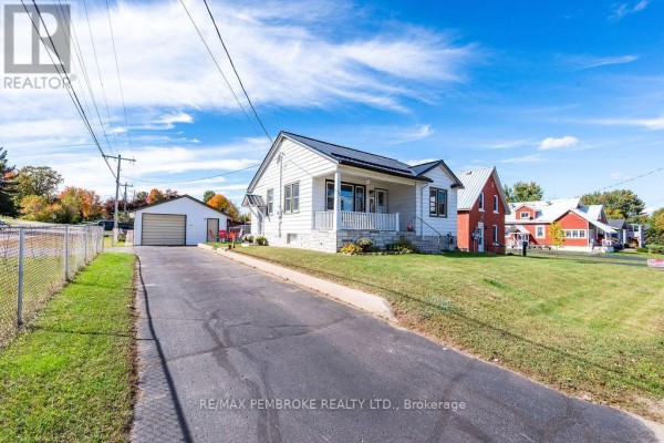 Driveway leading to a white house with a metal roof and detached garage, fenced yard to the left. - 53 Doran Street, Petawawa