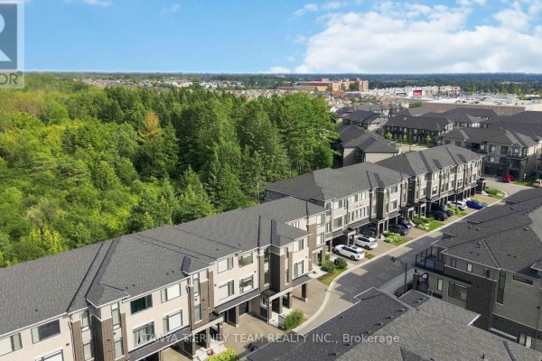 Aerial view of a residential street with rows of townhouses and distant buildings under a cloudy sky. - 53 Emmas Way, Whitby