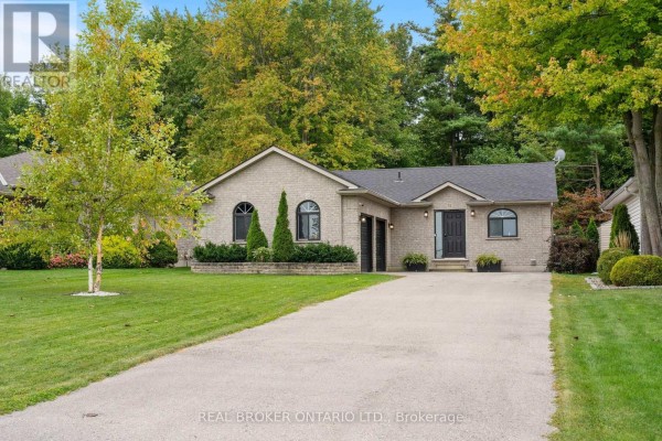 Daytime exterior of a light brick bungalow with a double garage, manicured lawn, and trees. - 53 Hawtrey Road N, Norfolk