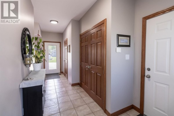 Dining room with marble-topped table and chairs, hardwood floor, and open view to living room. - 53 Laura St, Sault Ste  Marie
