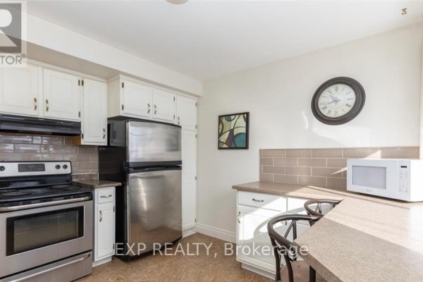 Kitchen with white cabinets, stainless steel appliances, a microwave, and a small breakfast bar. - 53 Madeira Drive, London East