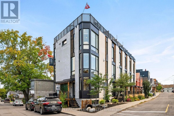Front exterior of a multi-story townhouse with white stone and dark metal accents. - 53 Merton Street, Ottawa