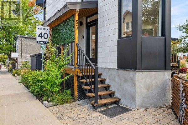 Entrance to a townhouse with wooden steps leading to a black front door. - 53 Merton Street, Ottawa