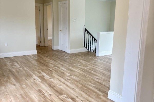 Interior view of light wood laminate flooring, doorways, and stairs with black spindles. - 53 Mood Road, Pleasant Lake