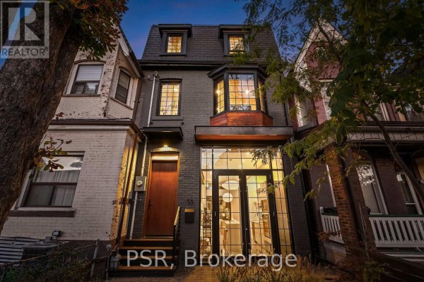 Front exterior of a dark grey brick townhouse with a mansard roof and large front windows. - 53 Palmerston Avenue, Toronto