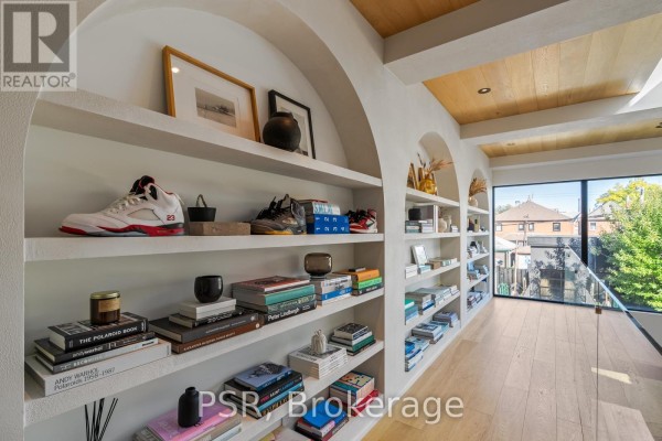 Built-in shelves with books and sneakers, large window, and wood ceiling - 53 Palmerston Avenue Toronto