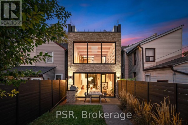 Rear exterior of a townhouse with brick and glass facade, overlooking a backyard patio. - 53 Palmerston Avenue, Toronto
