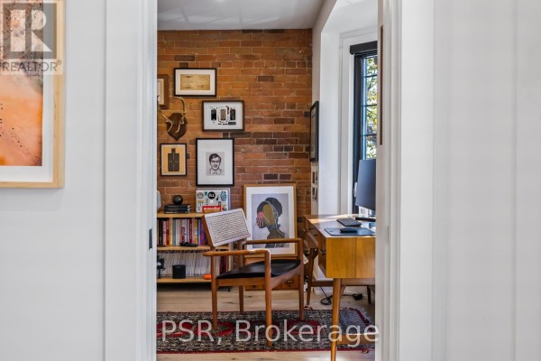 Exposed brick office with wooden desk, bookshelf, and artwork - 53 Palmerston Avenue Toronto