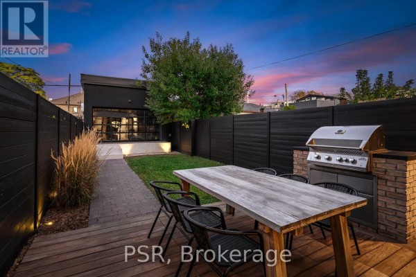 Backyard patio with wooden deck, outdoor dining set, built-in grill, and grassy area. - 53 Palmerston Avenue, Toronto