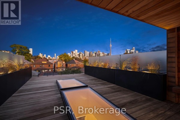 Rooftop deck with wooden flooring, planters, skylights, and a distant view of the Toronto skyline. - 53 Palmerston Avenue, Toronto