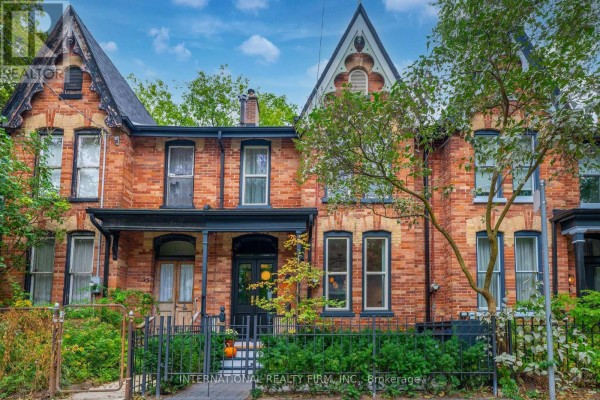 Close-up of a red brick townhouse with a black front door and porch. - 53 Spruce Street, Toronto
