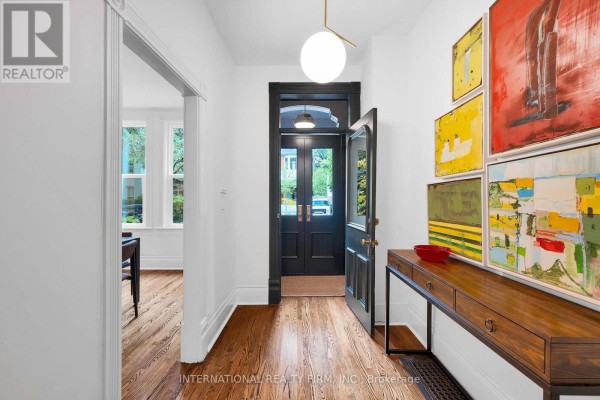 Interior hallway with hardwood floors, colorful art on wall, and console table. - 53 Spruce Street, Toronto