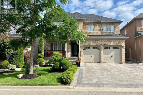 Front exterior of a two-story brick house with a covered porch, double garage, and manicured landscaping. - 53 Trinita Avenue, Vaughan