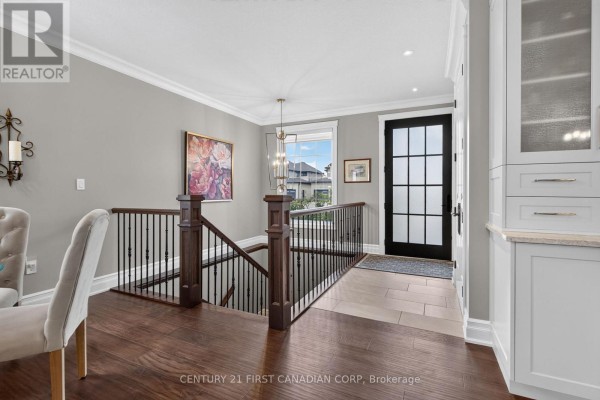 Interior hallway with a dark wood staircase, beige tiled floor, and white storage cabinets. - 53 Wayside Lane, Southwold