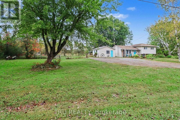 Wide shot of the property showing the house, detached garage, and large green lawn. - 53 West Avenue, North Grenville