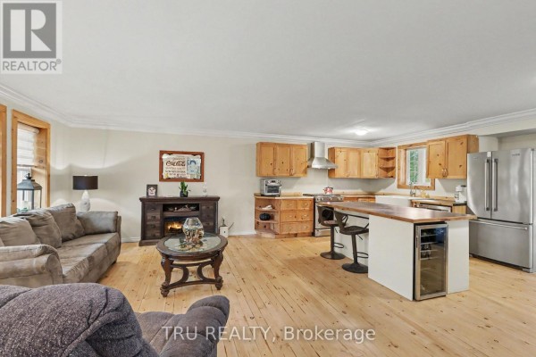 Open concept living and kitchen area with light wood floors, cabinets, and stainless steel appliances. - 53 West Avenue, North Grenville