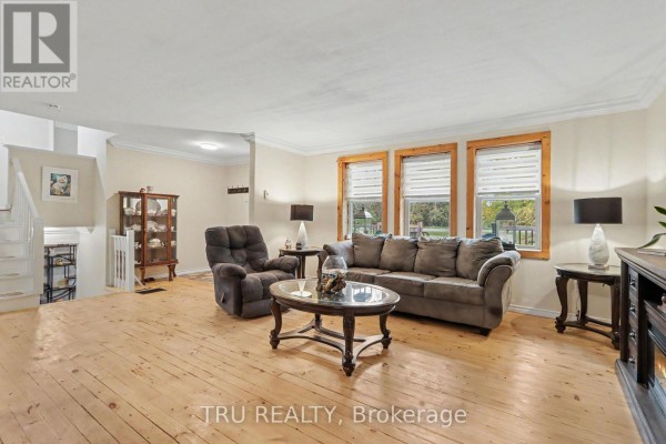 Living room with a sofa, recliner, coffee table, and large windows overlooking the backyard. - 53 West Avenue, North Grenville