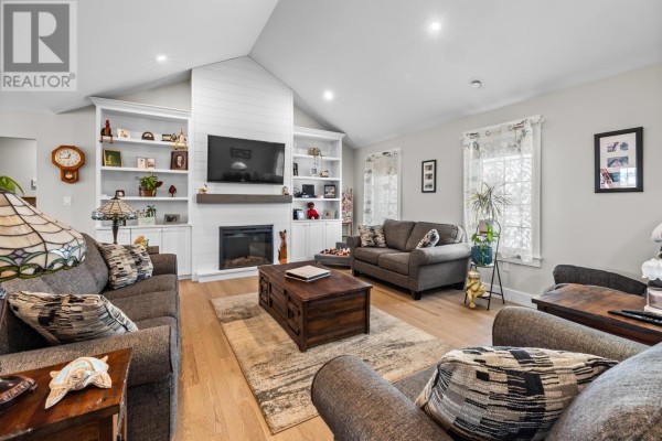 Living room with gray sofas, a fireplace, built-in white shelves, and wood flooring. - 53 Westville Road, New Dominion