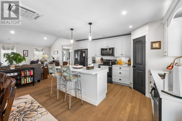 Living room and kitchen area with gray sofas, fireplace, white cabinetry, and island. - 53 Westville Road, New Dominion