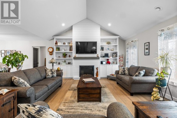 Spacious living room featuring multiple sofas, a fireplace, built-in shelving, and a pitched ceiling. - 53 Westville Road, New Dominion