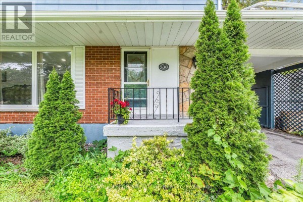Close-up of the front entrance of the house with a stone accent and manicured bushes. - 530 Brentwood Avenue, Oshawa
