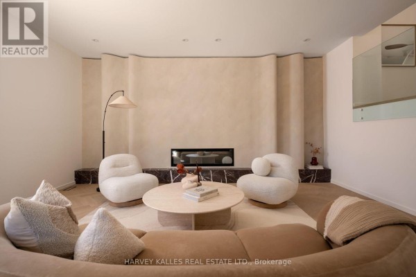 Living room fireplace with a modern linear fireplace and two white boucle armchairs. - 530 Duplex Avenue, Toronto