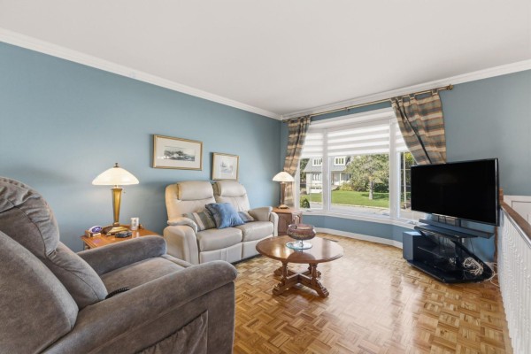 Living room with blue walls, a large bay window, plush seating, and parquet flooring. - 530 Rue De Bruyne, Gatineau