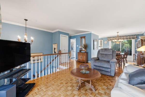 Living room and dining area with blue walls, parquet floors, a television, and stairs. - 530 Rue De Bruyne, Gatineau