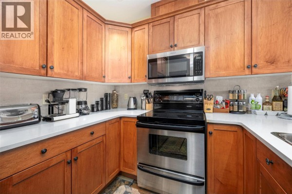U-shaped kitchen with wood cabinets, stainless steel appliances, and white countertops. - 5300 Big White Road Unit# 105, Big White