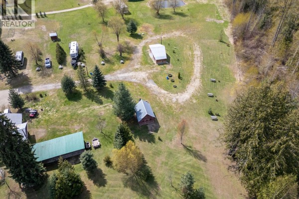 Overhead drone shot of a commercial property featuring a long green metal roof building and a red barn. - 5301(2-10)-5317-5323-5327 Prosh Frontage Road, Craigellachie