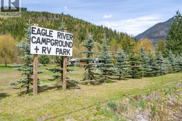 Wooden sign for "Eagle River Campground + RV Park" with evergreen trees and a building in the background. - 5301(2-10)-5317-5323-5327 Prosh Frontage Road, Craigellachie