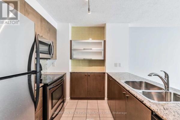 Kitchen with stainless steel appliances, granite countertops, and wood cabinetry. - 5302 - 11 Brunel Court, Toronto