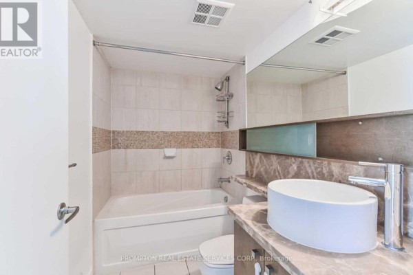 Bathroom with a bathtub, toilet, vanity, and a large mirror with shelving. - 5302 - 11 Brunel Court, Toronto