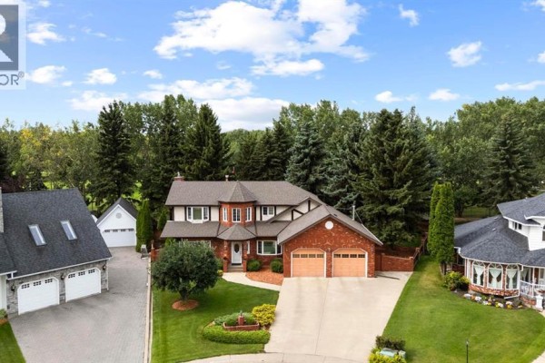 Aerial view of a large brick house with a pitched roof, attached garage, and manicured lawn. - 5302 61 Street Close, Camrose