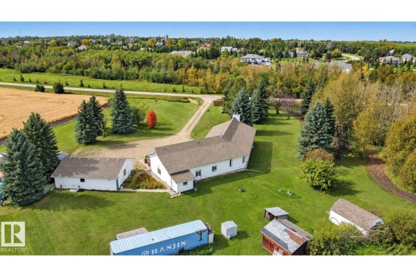 Aerial view of the property showing the rear of the house and outbuildings with grassy yards. - 53027 Rge Road 225, Rural Strathcona County