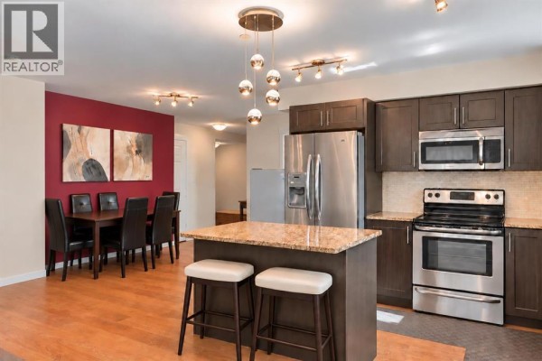 Hallway with white doors, dark grey carpet, and a white front door. - 5309, 755 Copperpond Boulevard Se, Calgary