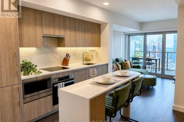 Modern kitchen with wood cabinets, white island, and city view beyond. - 5309 - 3 Concord Cityplace Way, Toronto