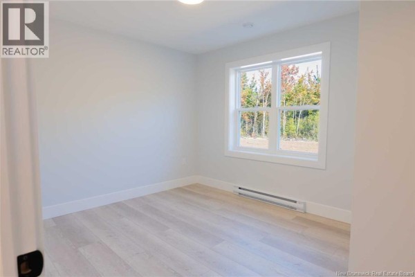 Empty bedroom with light gray walls, white trim, and a large window overlooking trees. - 531 Chem. Ward Road, Bouctouche