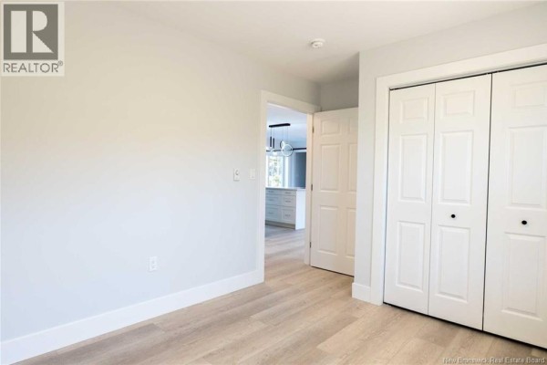 Interior hallway with light gray walls, white trim, a closet, and an open doorway to a kitchen. - 531 Chem. Ward Road, Bouctouche