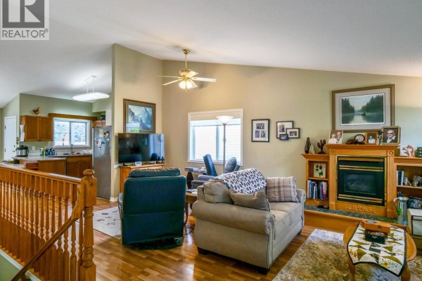 Living room with fireplace, built-in bookshelves, furniture, and view of the kitchen. - 531 Dawson Street, Quesnel