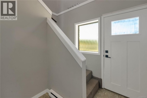 Living room with a fireplace, large windows, and wood-like flooring. - 531 Savary Cres, Campbell River