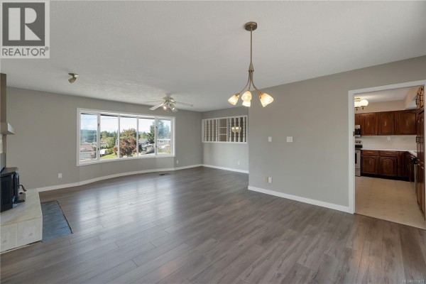 Spacious living area with a ceiling fan, large windows, and a built-in display cabinet. - 531 Savary Cres, Campbell River