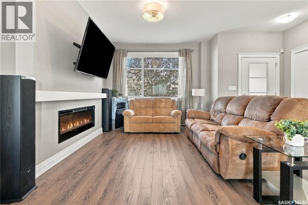 Living room featuring a linear fireplace, mounted television, and plush seating arrangements. - 5313 Green Silverberry Drive E, Regina