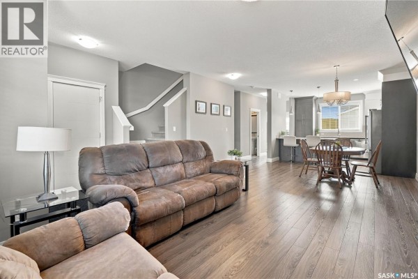 Open concept living and dining area with dark wood floors and a grey kitchen. - 5313 Green Silverberry Drive E, Regina