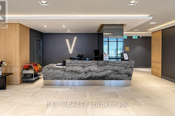Building lobby with a dark textured wall, modern reception desk, and wood accents. - 532 - 621 Sheppard Avenue E, Toronto