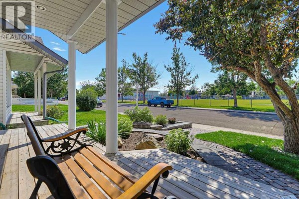 View from a wooden porch with two benches, looking across a street to a park. - 532 54 Avenue Sw, Calgary