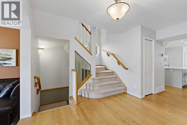 Interior staircase and hallway with light wood floors and neutral-colored carpeted stairs. - 532 54 Avenue Sw, Calgary