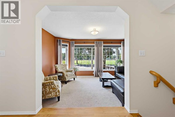 Living room with beige carpet, bay windows, and two patterned armchairs, viewed from the entryway. - 532 54 Avenue Sw, Calgary