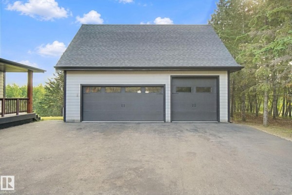 Close-up of a detached garage with two dark gray overhead doors and a lighter gray exterior. - 53203 Rge Road 15, Rural Parkland County
